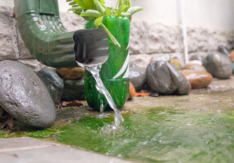 Regenwater stroomt uit een goot de grond in