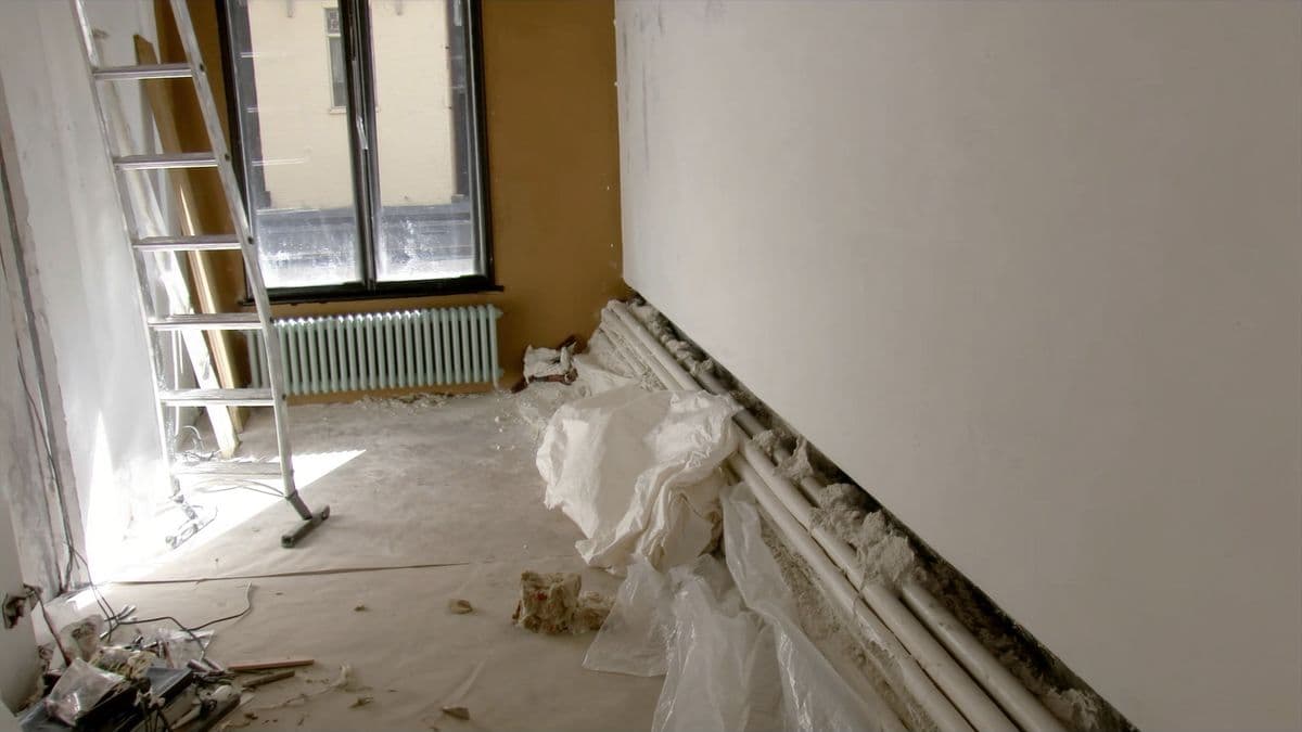 Een Nederlandse kamer tijdens een verbouwing met ladder, stofdoeken en een open vloer
